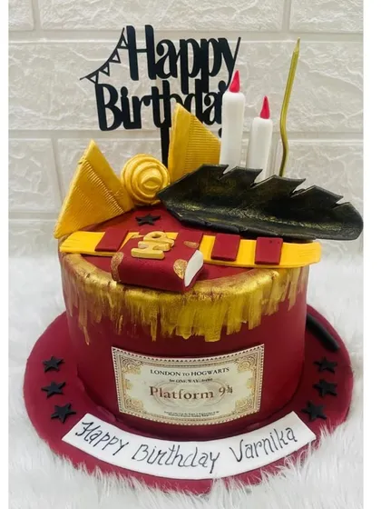 A magical Harry Potter cake for a true fan. This design includes iconic elements like the Gryffindor scarf, a spellbook, a feather quill, and a Platform 9¾ sign, all crafted from fondant.