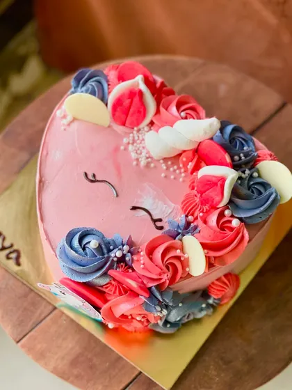 A close-up of the heart-shaped unicorn cake, showing the sleepy eyes and colorful buttercream mane.