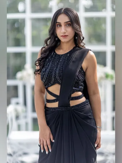 A close-up of the embellished blouse and cutout details on this modern black draped saree.