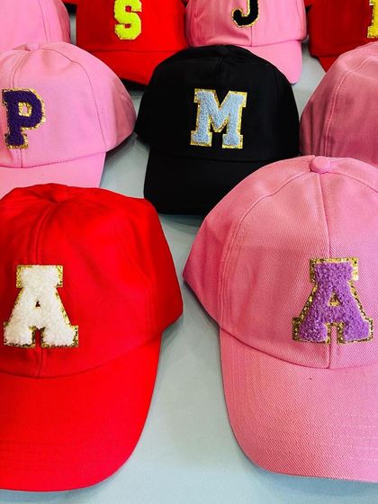 A colorful batch of personalized caps with various initials, ready to be gifted. These are a fun and practical return favor that guests will actually use.