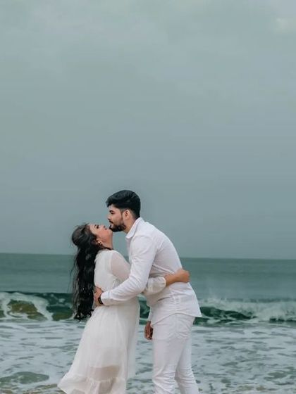 A romantic pre-wedding photo of a couple kissing on the beach, with the waves in the background. A timeless and beautiful shot.