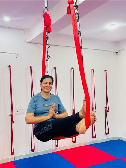 A smile of accomplishment is the best reward. This student is enjoying a moment of calm and balance in a supported Baddha Konasana (Bound Angle Pose) in the aerial hammock.