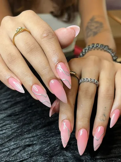 Feeling like a work of art with these long pink stiletto nails featuring an ombré effect and delicate silver chrome swirls.