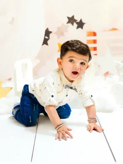 A baby boy crawls towards the camera, his face full of expression, during his first birthday shoot. Capturing their movement and energy is key.