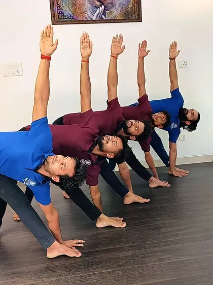 A group of male students practice Trikonasana (Triangle Pose), showing perfect synchronized alignment.