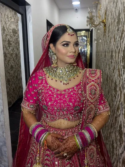 This bride radiates confidence in her pink wedding attire. The makeup features a defined contour and sharp winged eyeliner, balanced with a neutral lip color to keep the focus on her eyes.