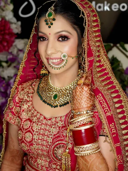 A classic getting-ready shot. This close-up captures the bride's flawless makeup, her beautiful smile, and the details of her nath and wedding jewelry.