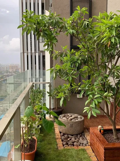 This is a high-rise balcony garden I designed, proving that you can have a green oasis anywhere in the city. You can see how a beautiful tree, a patch of green lawn, and a rustic stone water feature come together to transform this urban space.