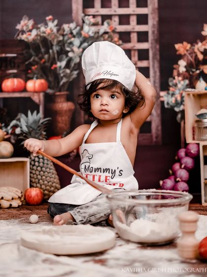 "Mommy's Little Helper" in action. This photo captures the playful spirit of the shoot as she adjusts her chef's hat while mixing up her floury creation.