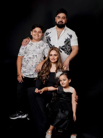A formal studio portrait of a family of four. The classic posing and coordinated outfits create a sophisticated and polished image that will be cherished for generations.