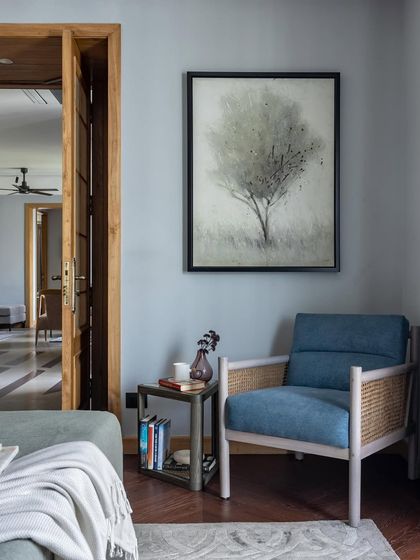A quiet corner in the Aalay living room, where a comfortable armchair and side table create an inviting spot for reading. The soft blue tones and natural textures contribute to the home's overall feeling of being a calm sanctuary in the city.