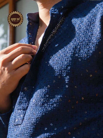 Elegance in every detail. A close-up of a navy blue kurta with all-over sequin and thread work, shimmering in the light.