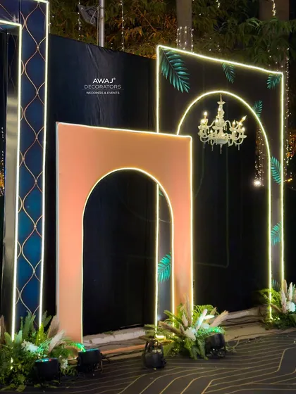 A close-up of the entrance decor, highlighting the combination of neon, chandeliers, and tropical leaf patterns.