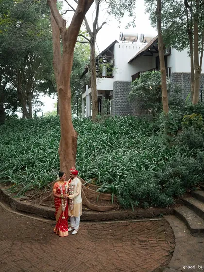 A wide shot of the couple at their beautiful outdoor wedding venue, showing the scale of the natural setting.