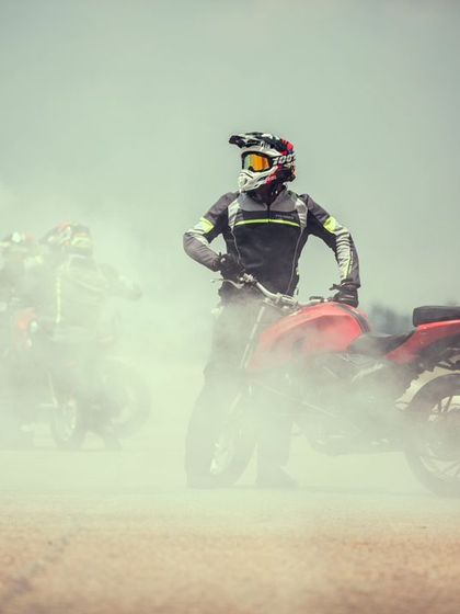 A stunt rider stands amidst the smoke, a moment of calm in the chaos. The professionalism and showmanship of our performers are second to none.