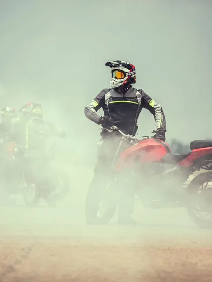 A stunt rider stands amidst the smoke, a moment of calm in the chaos. The professionalism and showmanship of our performers are second to none.