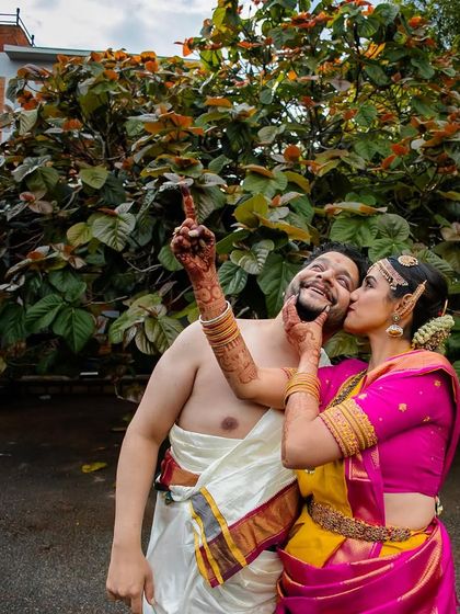 A playful and candid moment between a traditionally dressed couple. The groom's joyful expression and the bride's loving gesture make this a memorable shot.