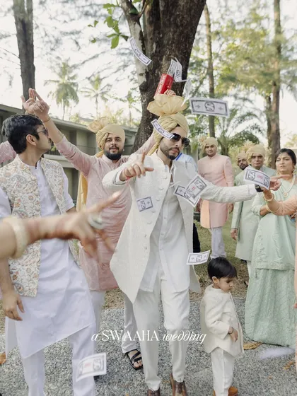 The groom's energetic entrance, dancing with his friends and family while fake money is showered on him in a fun baraat tradition.