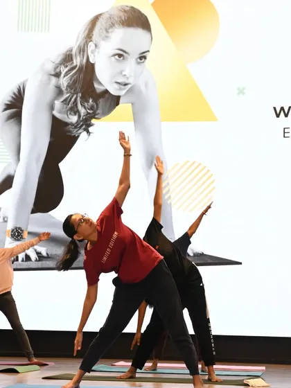 Participants engage in Trikonasana (Triangle Pose) during our fitness workshop with Samsung. This pose is excellent for stretching the entire body and building strength, making it a perfect addition to a corporate wellness program aimed at counteracting the effects of a sedentary workday.