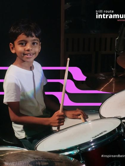 A young drummer smiles for the camera, ready for his performance. We make learning music fun and engaging for our youngest students.