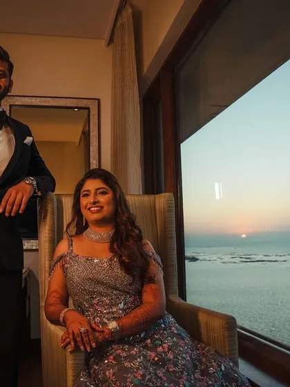 A classic portrait of the couple in their sea-facing room at Nariman Point. The setting sun over the water provides a stunning, natural backdrop for this elegant reception look.