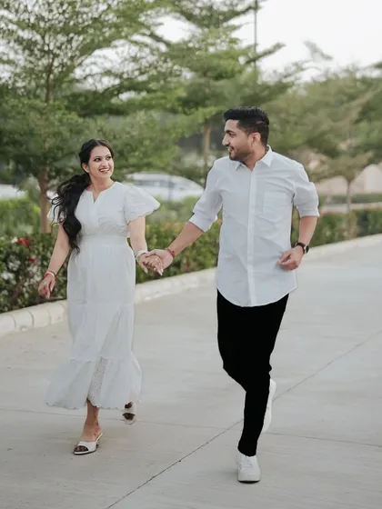 A candid and energetic shot of a couple running and laughing, capturing the pure joy of their pre-wedding moments.