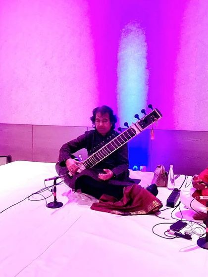 A performance shot with Ustad Rafique Khan and Sarfaraaz Khan under purple lighting.