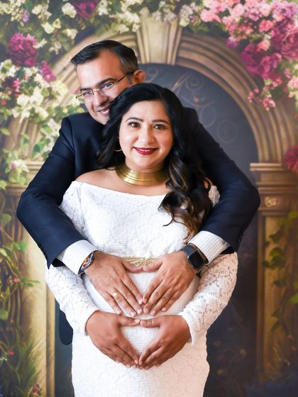 A heartwarming couple's portrait, with the dad-to-be making a heart shape with his hands on the baby bump.