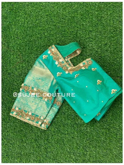 A flat-lay of the teal and green blouse, showing the rich texture of the silk sleeves and the subtle sparkle of the embroidery.