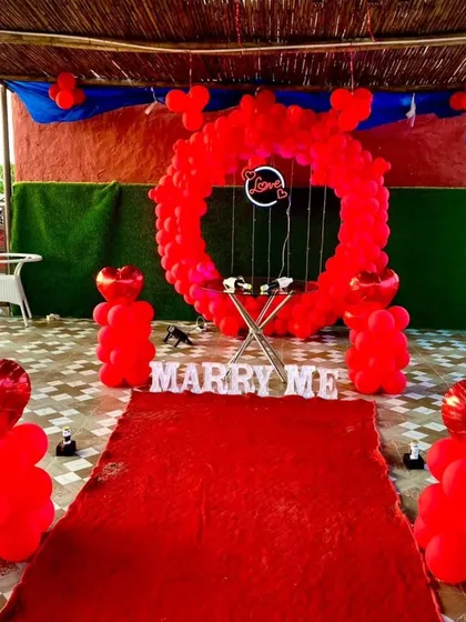 This proposal setup features a red carpet leading to the main display. The path is lined with balloon pillars, building anticipation for the "MARRY ME" reveal under a circular red balloon arch.