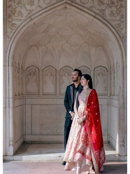 A classic portrait within a white marble alcove, reminiscent of royal elegance. The vibrant red dupatta adds a beautiful pop of color, making the image even more striking.