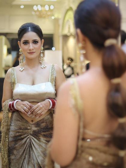 A modern and chic reception look. The client is looking in the mirror, showing off her smokey eyes and a trendy bubble ponytail.
