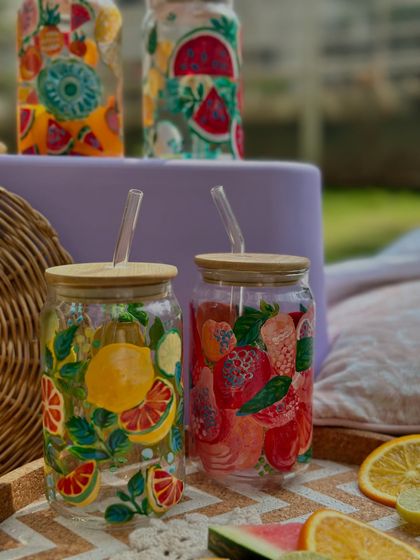 A pair of our fruity sipper jars, one with a lemon and citrus design and the other with a strawberry pattern. They make a beautiful set for a summer picnic.