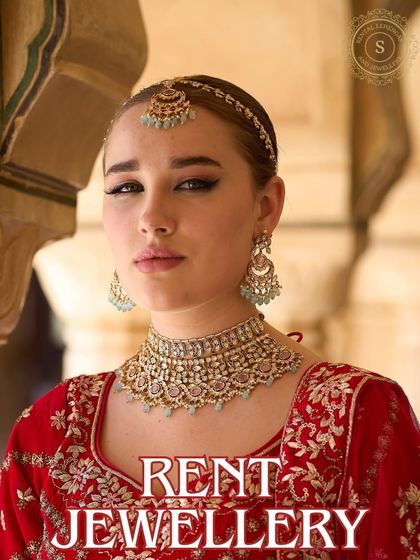 Make every moment magical in our designer jewellery. This model pairs a beautiful pastel choker set with a traditional red lehenga, a look you can easily rent.