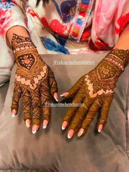 This heart-shaped design on the back of the hand is a popular choice for brides, symbolizing love amidst traditional patterns.