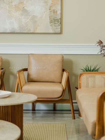 A close-up of the custom-designed armchair, featuring tan leather and a cane-detailed wooden frame. This piece perfectly blends modern comfort with classic materials.