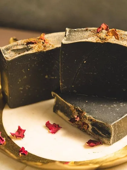 This is my 'Barood' charcoal body bar, made with goat's milk and activated charcoal. It’s a powerful yet gentle cleanser that detoxifies the skin, and the dried rose petals are a little touch of beauty I love to add.