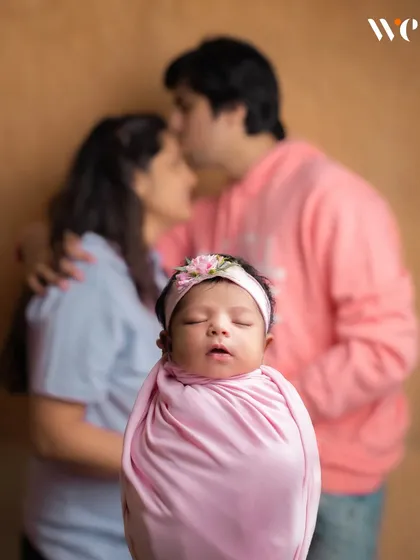 This artistic shot tells a beautiful story. By focusing on the baby while showing the parents' affection in the background, we create a portrait that represents the love that created this new family.