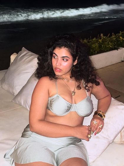 Lounging on a daybed at Finns Beach Club. The silver co-ord set and stacked jewelry create a glamorous, beach-party look.