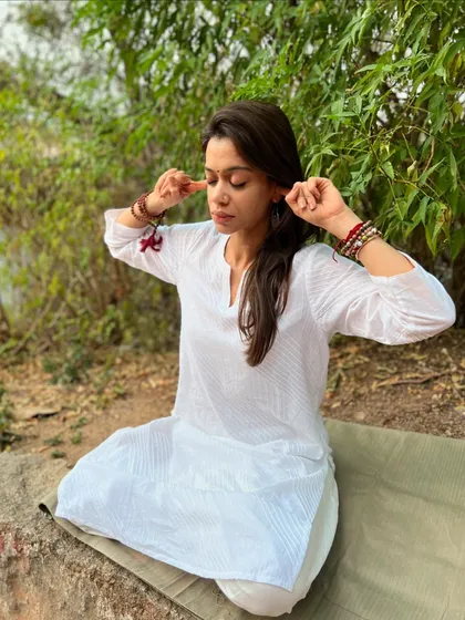 Practicing Bhramari Pranayama (Bee Breath) outdoors, a calming breathing technique that soothes the nervous system.