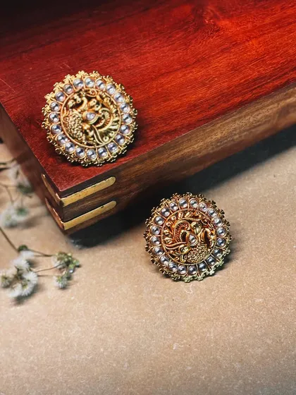 Intricate peacock-motif studs, detailed with fine gold work and a border of delicate pearls. A small piece of wearable art.