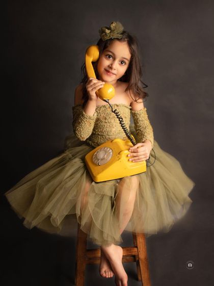 A vintage-inspired portrait with a classic rotary phone prop. Her pose and the olive green dress create a timeless, storybook feel.