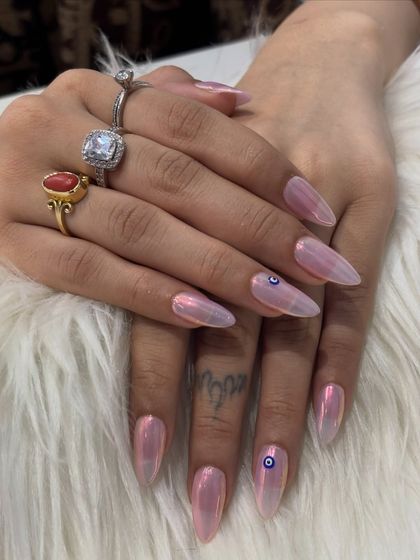 A close-up shot focusing on the flawless finish of the pink chrome and the tiny evil eye detail. It shows how a small piece of art can add so much personality to a manicure.