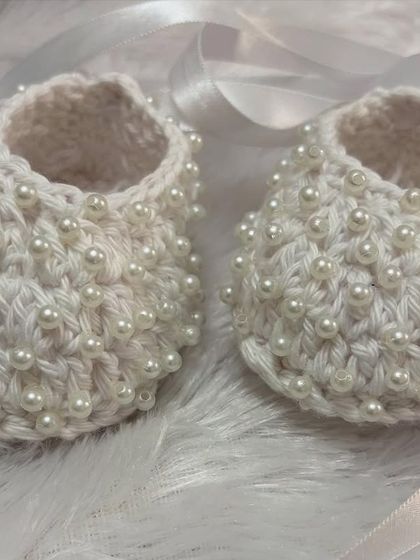 A close-up of my pearl-studded baby shoes, crafted with soft Ganga Desire yarn. The pearls are securely woven in for a beautiful and durable design.