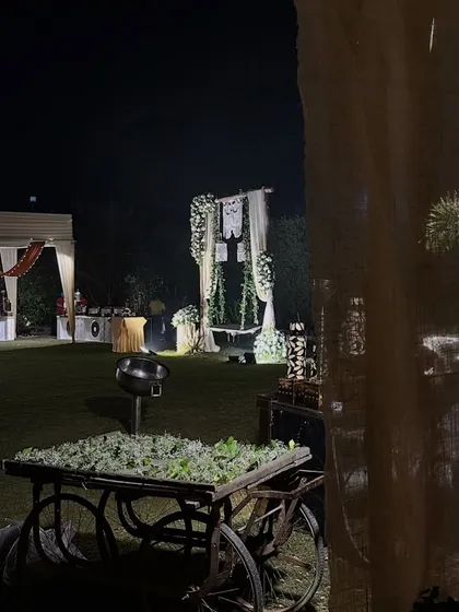 A wide shot of the rustic-themed event space, featuring a decorated cart with flowers and a beautiful swing in the background.