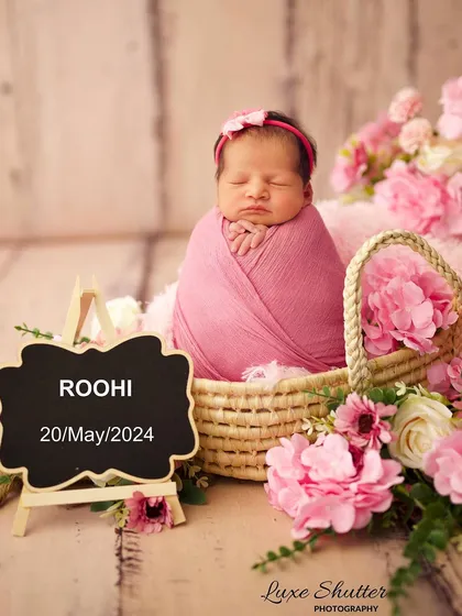 A personalized setup with a chalkboard announcing the baby's name and birthdate, nestled in a basket of pink flowers.