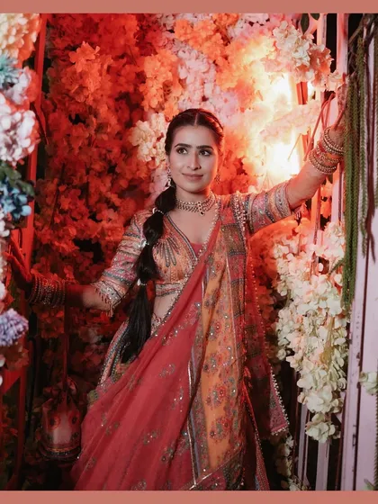 A solo portrait of the bride Kiran, radiant and happy against a backdrop of colorful flowers at her carnival-themed wedding event.