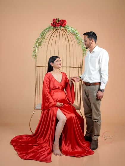 A romantic pose using our golden birdcage prop. The mom-to-be is seated while her partner stands beside her, creating a beautifully composed and elegant shot.