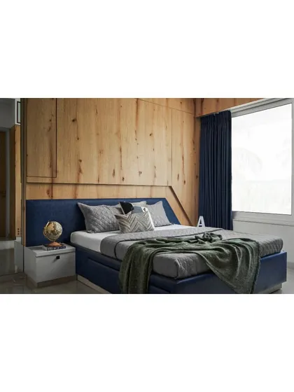 The teenager's bedroom, featuring a blue upholstered bed set against a backdrop of knotty pine veneer wall paneling.