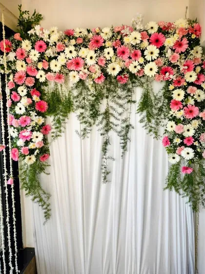 A simple yet elegant backdrop created with pink and white gerbera daisies and cascading green ferns. This design is perfect for adding a touch of floral beauty without overwhelming the space.